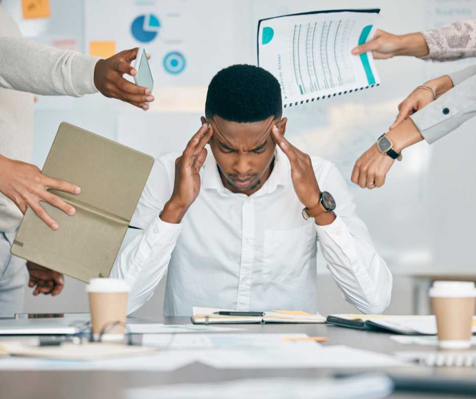 A man is surrounded by tasks and people drawing his attention, causing anxiety.